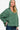 Side profile of a woman in a green brushed Hacci hoodie, showcasing the high-low hem and slit details.