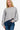 Women's grey asymmetric hem sweater with long sleeves, styled with blue jeans.