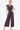 Model in Purple Laced Surplice Jumpsuit with a tie waist and eyelet details.